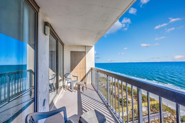 balcony with a water view and a view of the beach