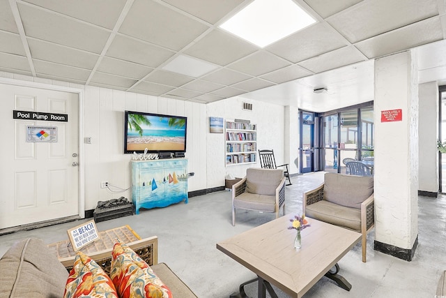 living room with concrete flooring and a paneled ceiling