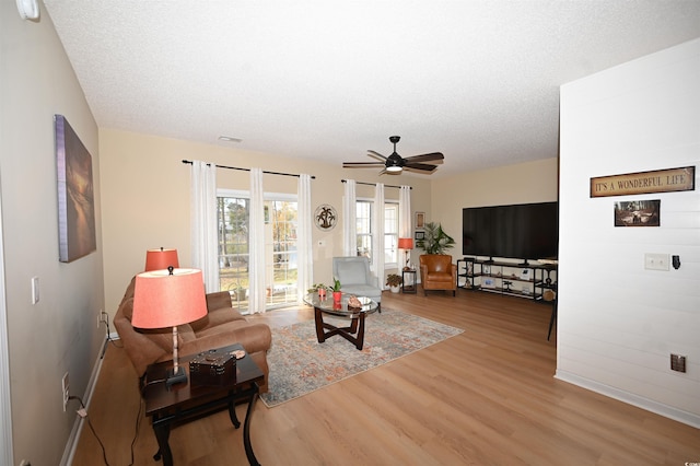 living room featuring a textured ceiling, hardwood / wood-style flooring, and ceiling fan