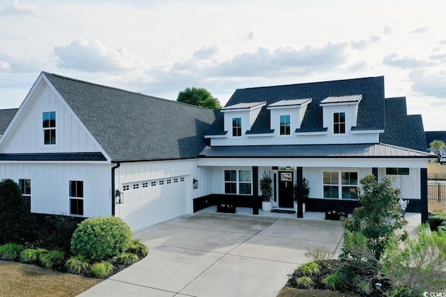 view of front of property with an attached garage, a standing seam roof, board and batten siding, driveway, and metal roof