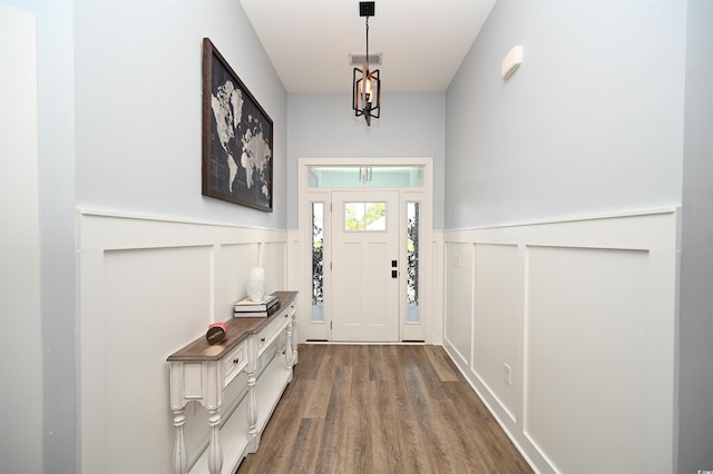 doorway with a decorative wall, dark wood-style flooring, and a wainscoted wall