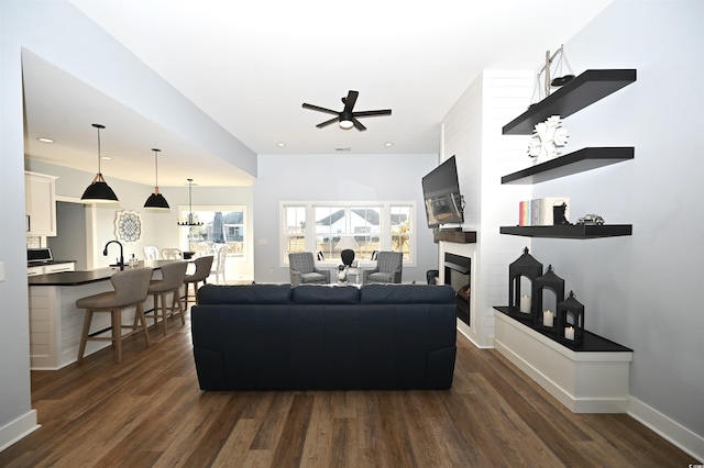 living area with baseboards, dark wood-style floors, a fireplace, and ceiling fan
