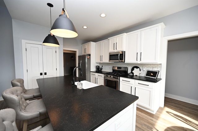 kitchen with pendant lighting, appliances with stainless steel finishes, tasteful backsplash, a kitchen bar, and white cabinetry