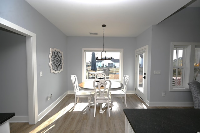 dining room featuring an inviting chandelier, wood finished floors, visible vents, and plenty of natural light