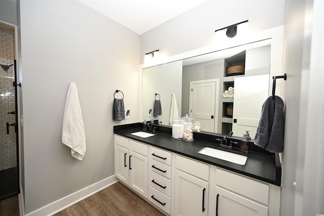 full bathroom with baseboards, wood finished floors, a sink, and double vanity