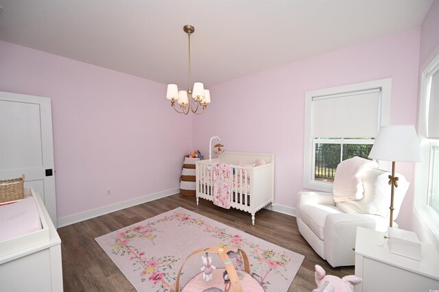 bedroom with dark hardwood / wood-style flooring, a chandelier, and a crib