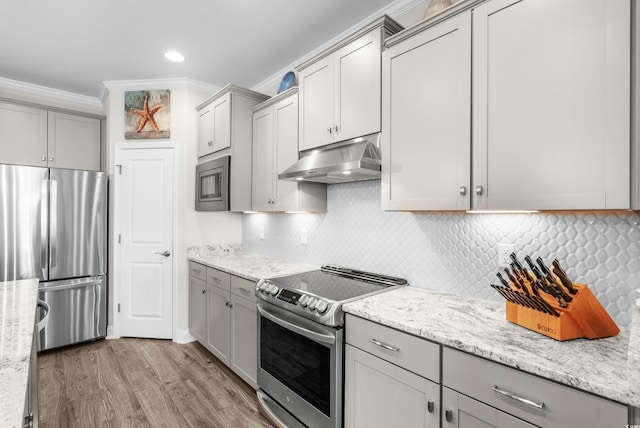 kitchen with gray cabinets, appliances with stainless steel finishes, light wood-type flooring, ornamental molding, and under cabinet range hood