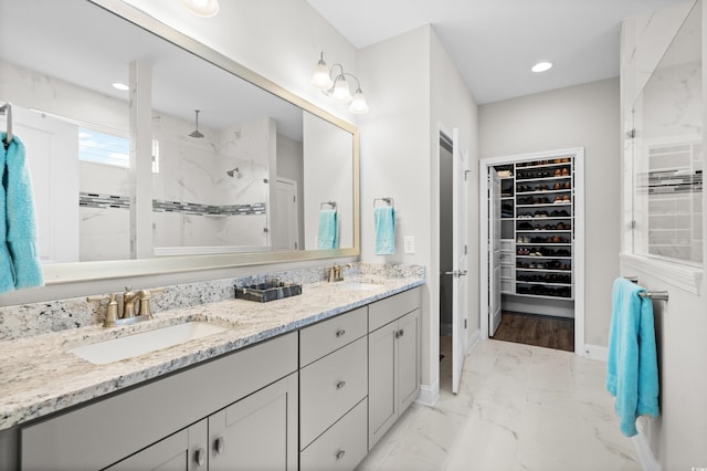 bathroom featuring a sink, baseboards, a tile shower, and a spacious closet