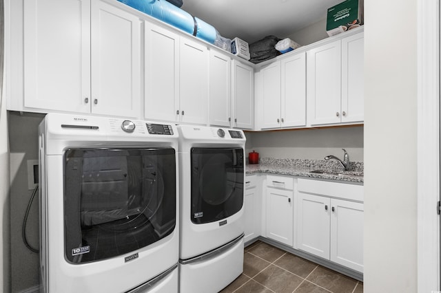 laundry room featuring washing machine and clothes dryer, dark tile patterned flooring, a sink, and cabinet space
