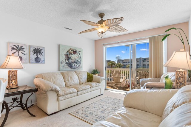 carpeted living room featuring ceiling fan and a textured ceiling