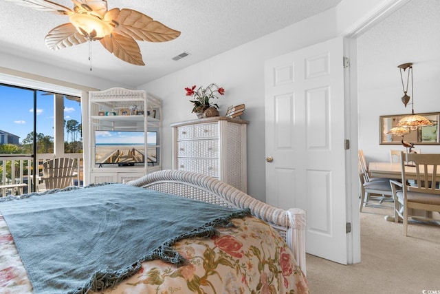 carpeted bedroom with ceiling fan, access to exterior, and a textured ceiling