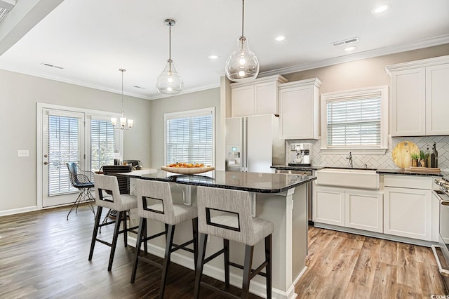 kitchen with white refrigerator with ice dispenser, a center island, white cabinets, and sink