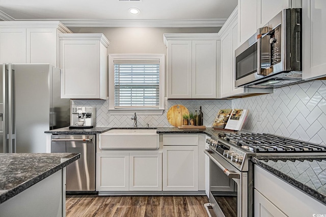 kitchen with dark stone counters, white cabinetry, sink, and stainless steel appliances