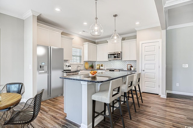 kitchen featuring decorative backsplash, stainless steel appliances, dark wood-type flooring, white cabinets, and a kitchen island