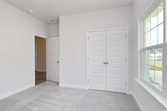 unfurnished bedroom featuring a closet and light colored carpet