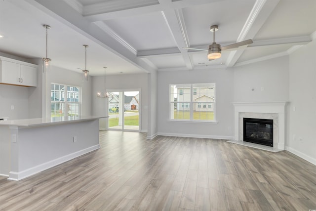 unfurnished living room with ceiling fan, a fireplace, coffered ceiling, and light hardwood / wood-style flooring