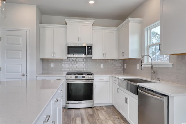 kitchen featuring white cabinets, backsplash, sink, and stainless steel appliances