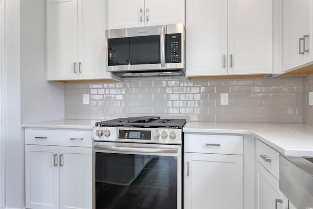 kitchen with tasteful backsplash, white cabinets, and stainless steel appliances