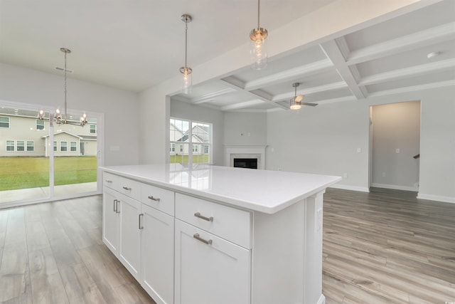 kitchen with white cabinets, beam ceiling, hanging light fixtures, and coffered ceiling