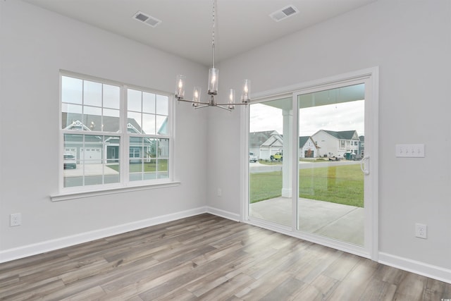 unfurnished dining area with plenty of natural light, wood-type flooring, and a chandelier