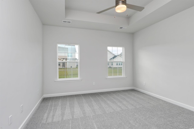 carpeted spare room with a tray ceiling and ceiling fan