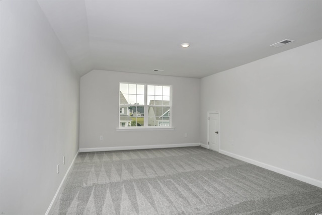 empty room featuring light colored carpet and vaulted ceiling