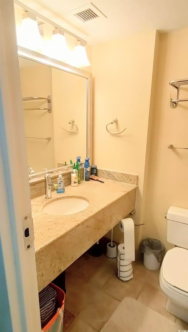 bathroom featuring toilet, sink, and tile patterned flooring