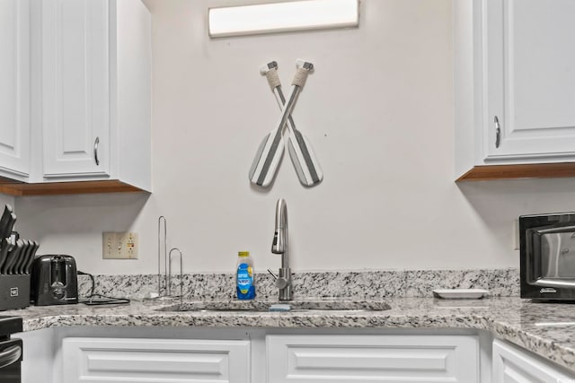 kitchen featuring white cabinets, light stone countertops, sink, and an AC wall unit