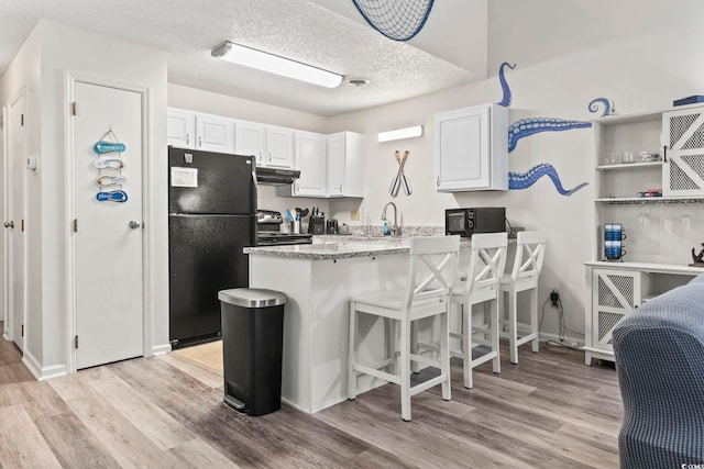 kitchen with white cabinets, light hardwood / wood-style flooring, black appliances, and a textured ceiling