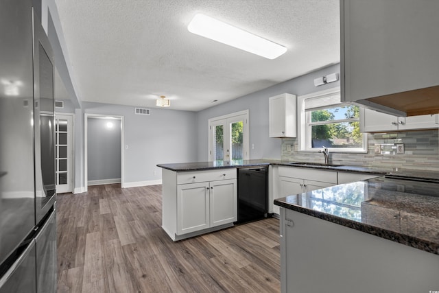 kitchen featuring sink, black dishwasher, kitchen peninsula, stainless steel fridge, and white cabinets