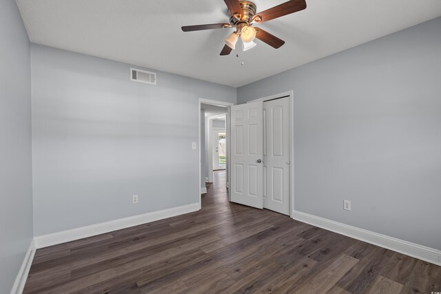 unfurnished bedroom with a closet, dark hardwood / wood-style floors, and ceiling fan