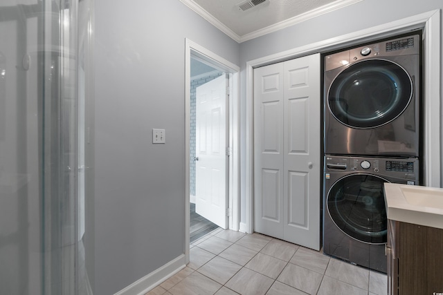 washroom featuring crown molding, stacked washer / drying machine, and light tile patterned flooring