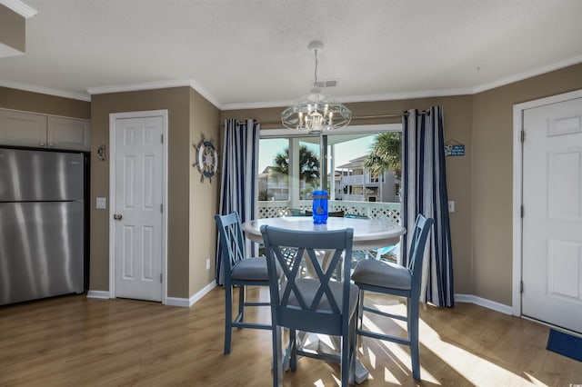 dining area with light wood-type flooring, crown molding, and an inviting chandelier