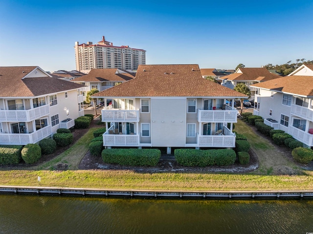 rear view of house featuring a balcony and a water view