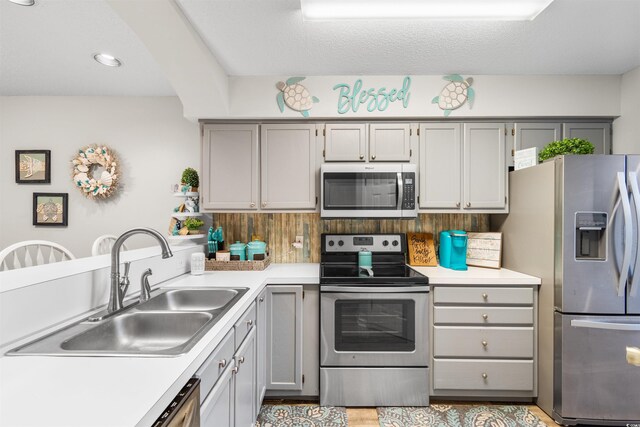 kitchen with gray cabinetry, sink, tasteful backsplash, a textured ceiling, and appliances with stainless steel finishes