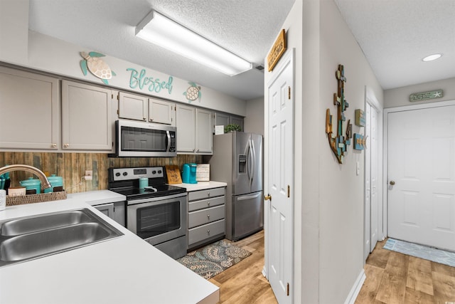 kitchen featuring a textured ceiling, stainless steel appliances, gray cabinets, and sink