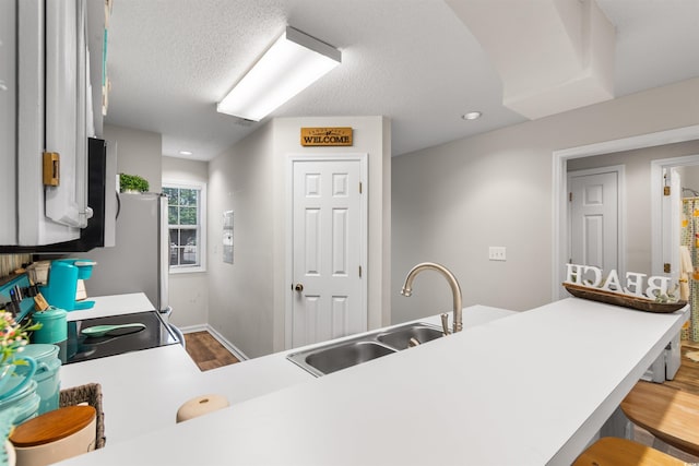 kitchen featuring a kitchen breakfast bar, wood-type flooring, kitchen peninsula, and sink