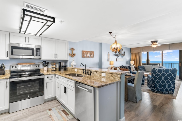 kitchen featuring kitchen peninsula, white cabinetry, a water view, and appliances with stainless steel finishes