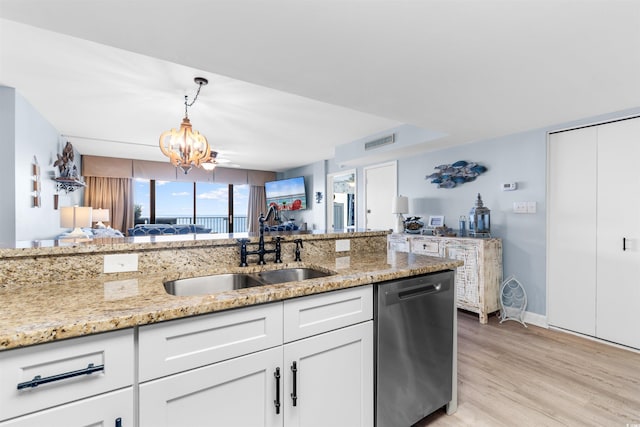 kitchen featuring light stone countertops, white cabinetry, sink, stainless steel dishwasher, and a notable chandelier