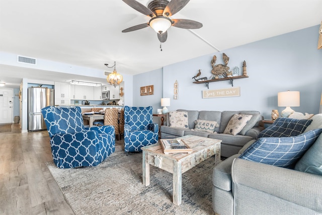 living room with hardwood / wood-style floors and ceiling fan with notable chandelier