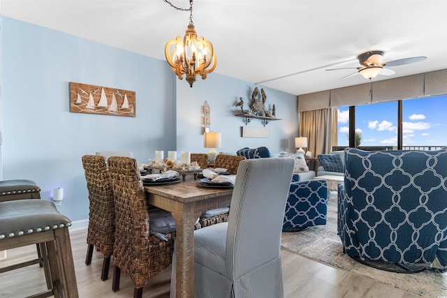 dining area with hardwood / wood-style flooring and ceiling fan with notable chandelier