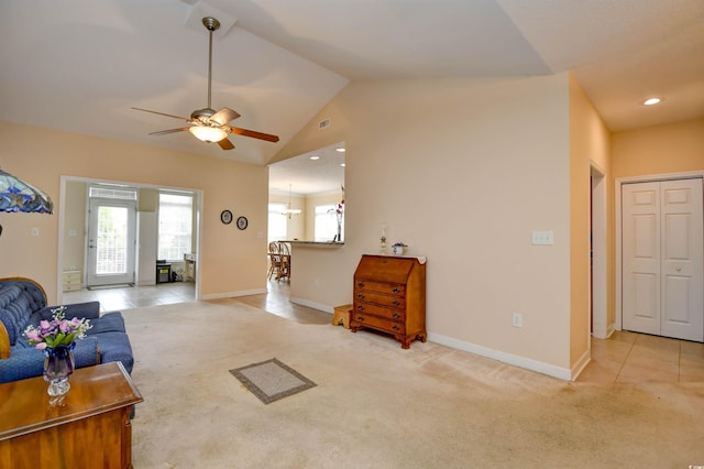 living room with ceiling fan with notable chandelier, light colored carpet, and vaulted ceiling