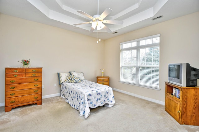 carpeted bedroom featuring a tray ceiling and ceiling fan