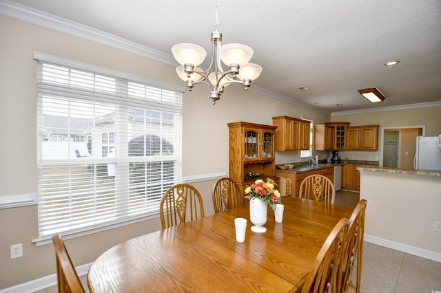 tiled dining room with a chandelier, crown molding, and sink