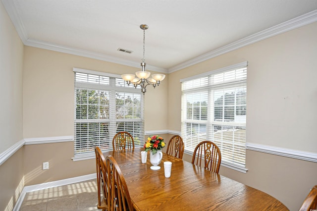 dining room with tile patterned floors, crown molding, and a chandelier