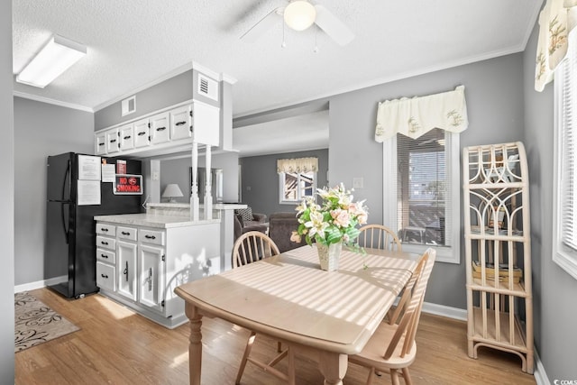 dining room with light wood-type flooring, a textured ceiling, ceiling fan, and ornamental molding