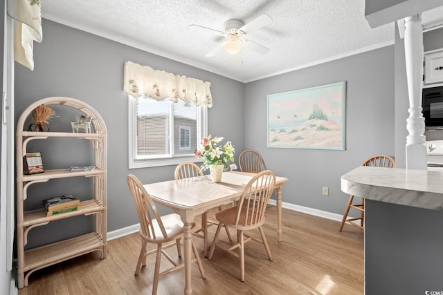 dining room with ornate columns, ceiling fan, a textured ceiling, and light wood-type flooring