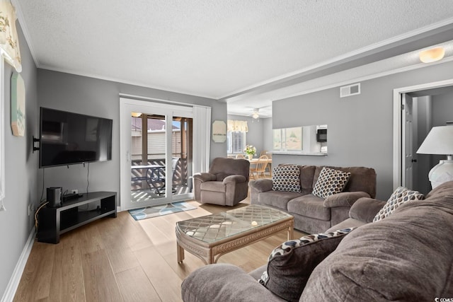 living room with ceiling fan, ornamental molding, a textured ceiling, and light hardwood / wood-style flooring