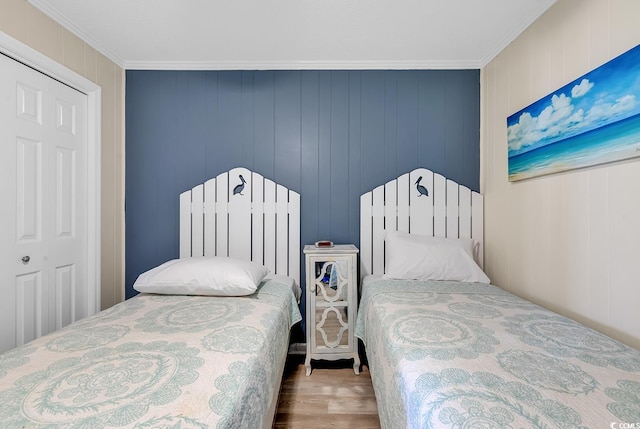 bedroom featuring a closet, ornamental molding, and wood walls