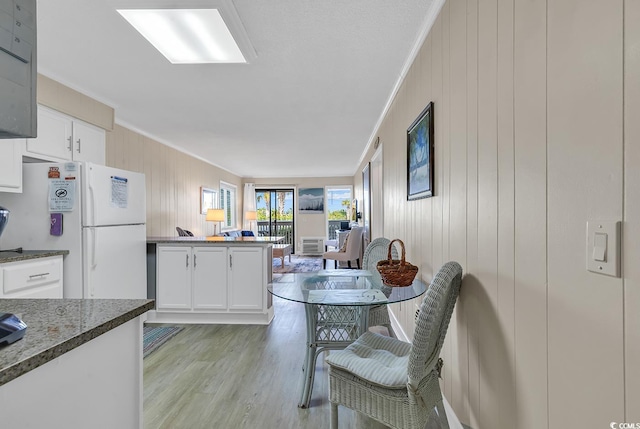 kitchen with white fridge, white cabinetry, and crown molding